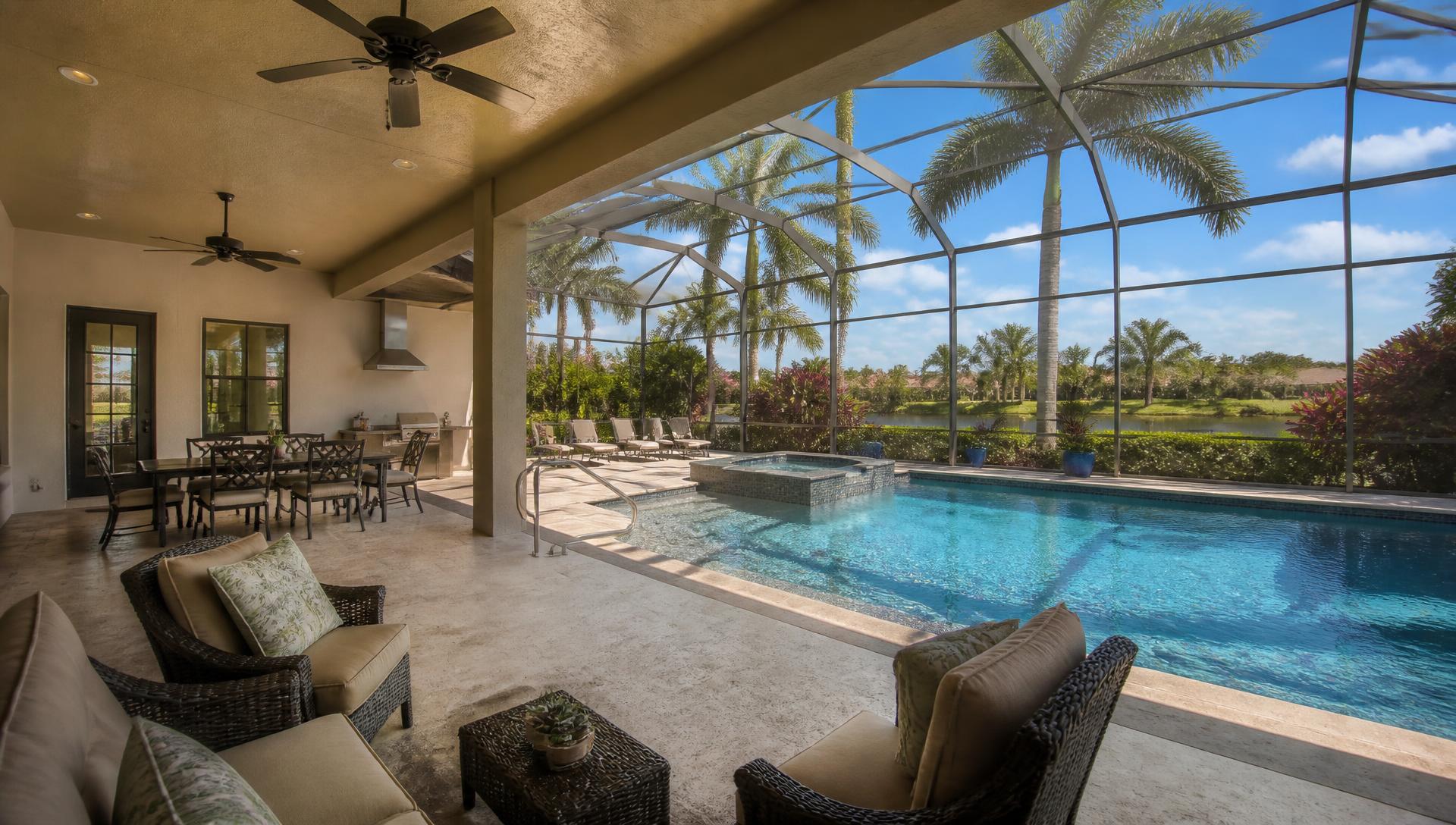 Screened lanai pool deck of a Southwest Florida home with shaded patio furniture and a bright sunlit swimming pool and palm trees