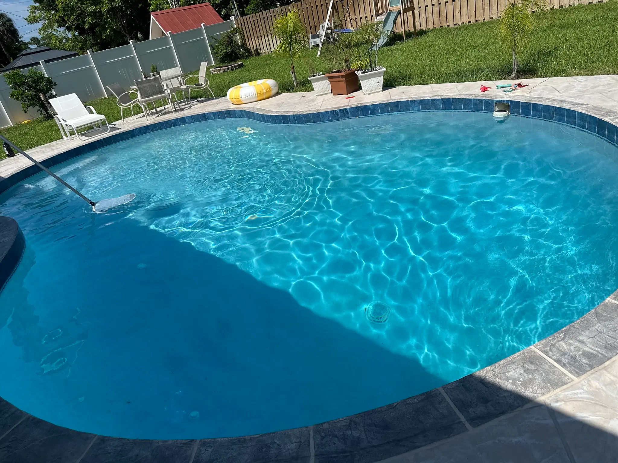 Large kidney-shaped backyard pool with sun shelf and balanced blue water in Estero, FL