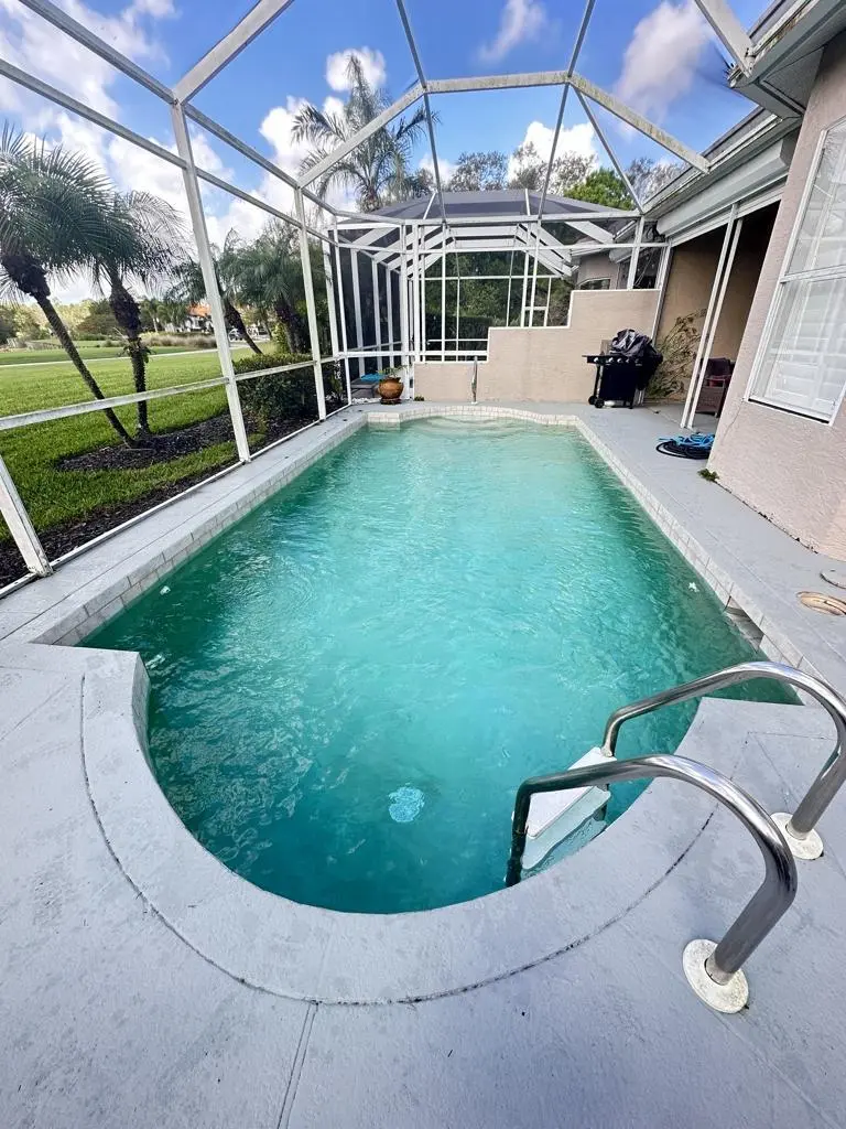 Sparkling pool water with stainless steel handrail inside a Florida pool cage