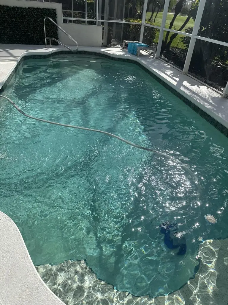 Screened pool with robotic cleaner working across a clear pool floor in Naples, FL
