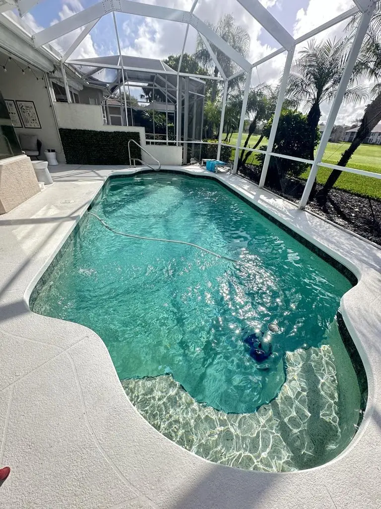 Freeform pool with attached spa under a screen enclosure in Bonita Springs, FL