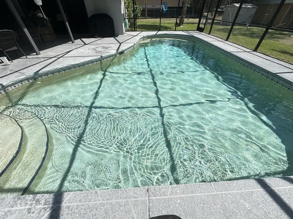 Large screened pool with tanning ledge and clear turquoise water in Estero, FL